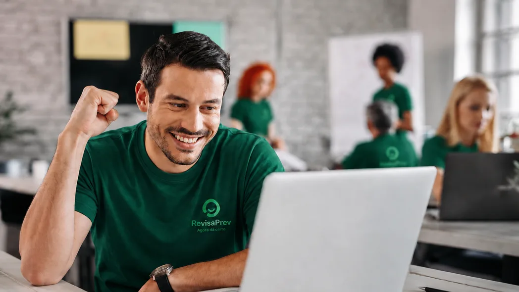 Atendente da RevisaPrev comemorando diante do computador no escritório